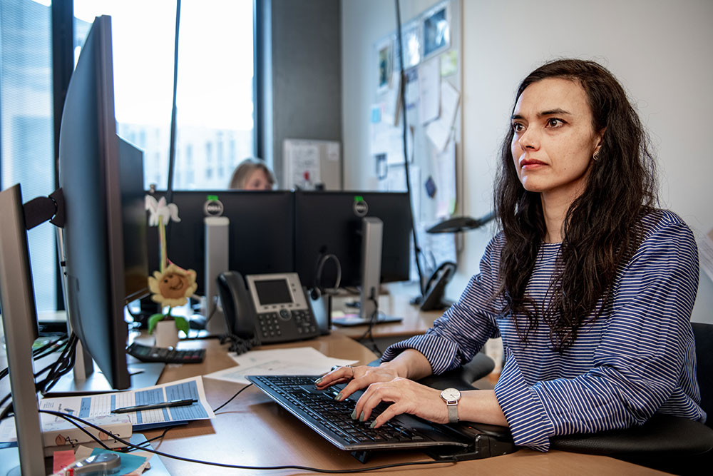 Kvinde sidder ved computerskærm på kontor. Her er ergonomi vigtigt.