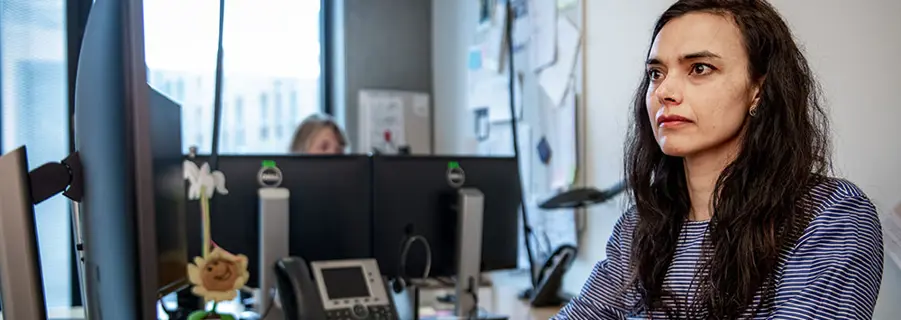 Kvinde sidder ved computerskærm på kontor. Her er ergonomi vigtigt.