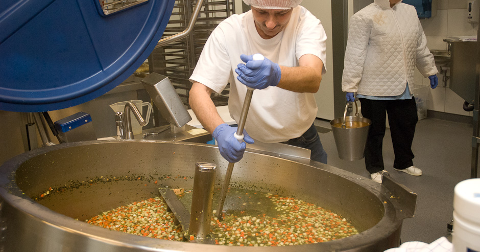 Billede af mand, der rører i en stor beholder. Arbejdet giver risiko for nedslidning.