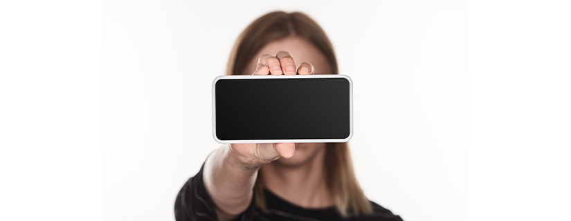 Kvinde holder telefon i hånden - digital mobning kan foregå alle steder.